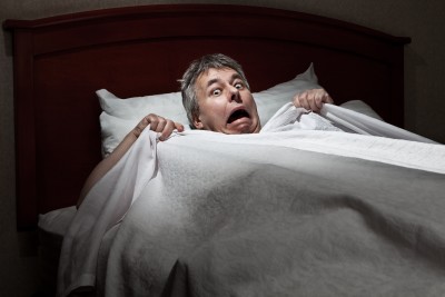 man wakes up from sleep with sleep paralysis scared and confused